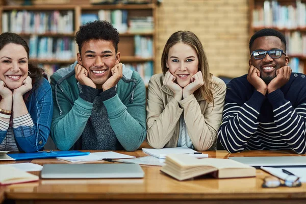 Vzdělání je bránou k větším věcem. Portrét skupiny vysokoškolských studentů sedících v knihovně na kampusu. — Stock fotografie