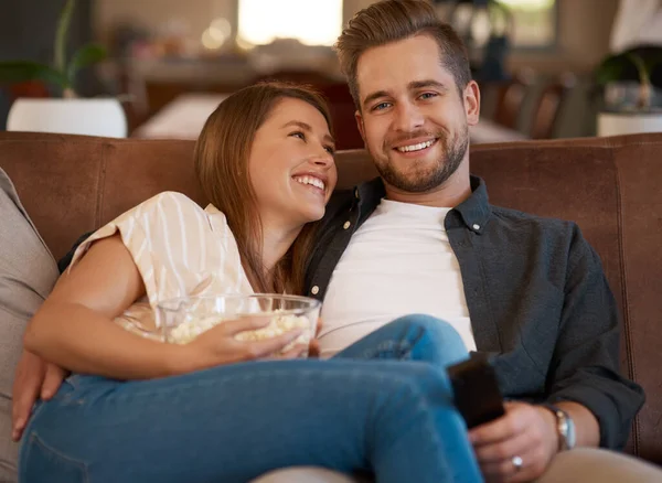 Telewizja jest najpopularniejszą i najlepszą formą rozrywki. Przycięte zdjęcie młodej pary relaksującej się popcornem na kanapie w domu. — Zdjęcie stockowe