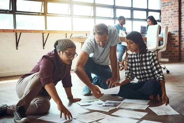 Ensemble, nous pouvons créer des idées de réussite. Prise de vue d'une équipe d'entrepreneurs collaborant et assis sur le sol dans un bureau moderne. — Photo