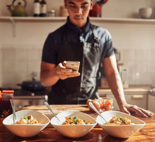 El genio culinario ataca de nuevo. Fotografía de un joven usando un smartphone para tomar fotos de una comida saludable que preparó en casa. —  Fotos de Stock
