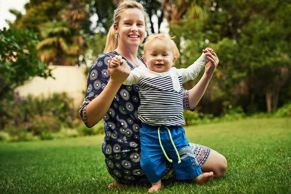 最初の一歩だ。かわいい男の子と彼の母親のショットの裏庭で遊んで. — ストック写真