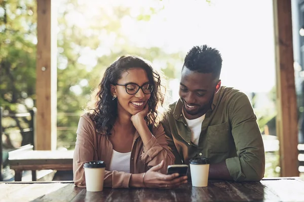 Expressando seu sentimento através de emojis. Tiro de uma mulher usando seu celular enquanto estava sentada em um café com seu namorado. — Fotografia de Stock