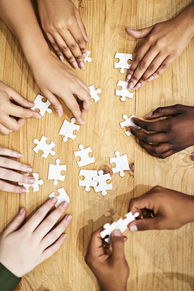 Risolvere i problemi come professionisti. Girato di un gruppo di persone che costruiscono un puzzle insieme. — Foto Stock