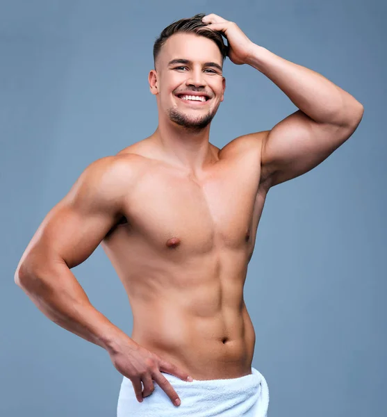 Мужская простота его красота. Студийный портрет мускулистого молодого человека, позирующего в полотенце на сером фоне. — стоковое фото