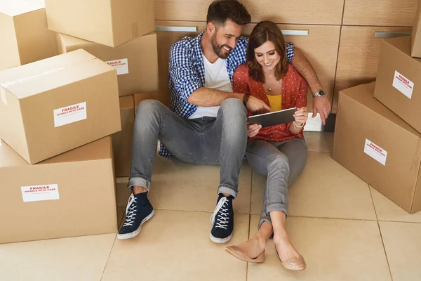 Planificación de sus ideas de decoración interior en línea. Fotografía de una joven pareja tomando un descanso mientras se mudan a su nuevo hogar. —  Fotos de Stock