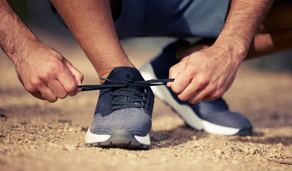 Machen Sie sich bereit, seine Cardio-Zeit. Nahaufnahme eines nicht erkennbaren Mannes, der seine Schnürsenkel bindet, während er im Freien trainiert. — Stockfoto