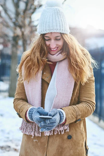A mandar SMS a todos para virem juntar-se a mim na neve. Tiro de uma jovem atraente usando um celular na neve fora. — Fotografia de Stock
