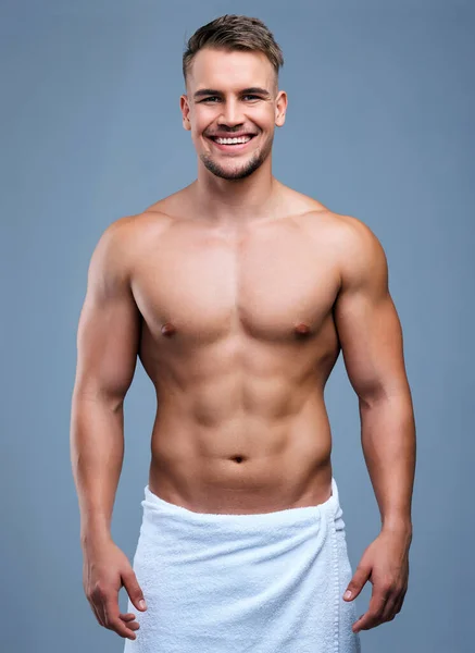 Vite un viaggio mostrato dal tuo corpo. Studio ritratto di un giovane muscoloso in posa in un asciugamano su uno sfondo grigio. — Foto Stock