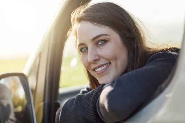 Jag är sugen på en roadtrip. Porträtt av en glad ung kvinna tittar ut genom fönstret på sin bil medan ute på en roadtrip. — Stockfoto