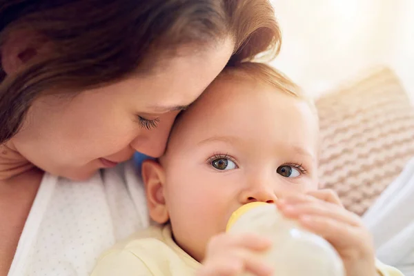 Je bent geliefd, kleintje. Schot van een baby die zijn fles drinkt terwijl hij in zijn moeders armen ligt. — Stockfoto