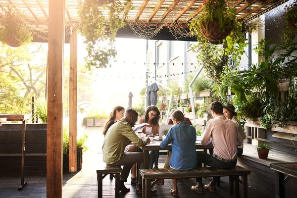 Theyre working out in the fresh air today. Shot of a group of designers having a meeting at a coffee shop. — Stock Photo, Image