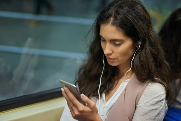 Den perfekta tiden att komma ikapp på sociala medier. Beskuren bild av en ung attraktiv kvinna som använder en mobiltelefon när pendlar med tåget. — Stockfoto