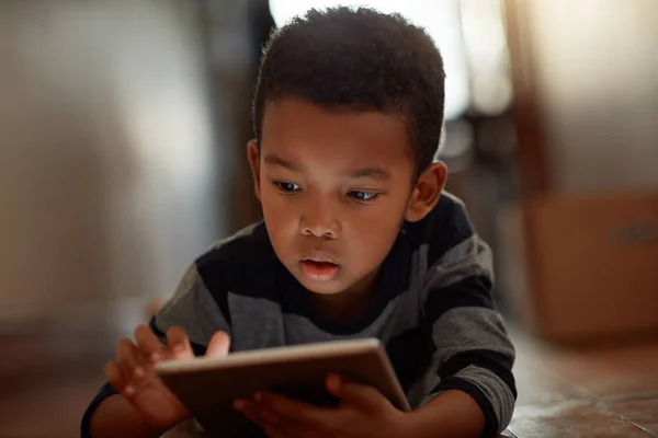 Crecer con la tecnología. Fotografía de un niño usando su tableta digital mientras yacía en el suelo en casa. —  Fotos de Stock