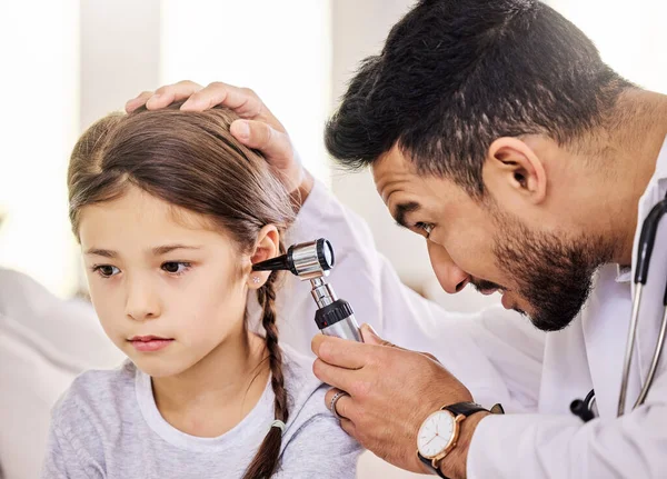De dokter kijkt vandaag naar mijn oren. Schot van een arts met behulp van een otoscoop om een kleine meisjes oor te onderzoeken. — Stockfoto