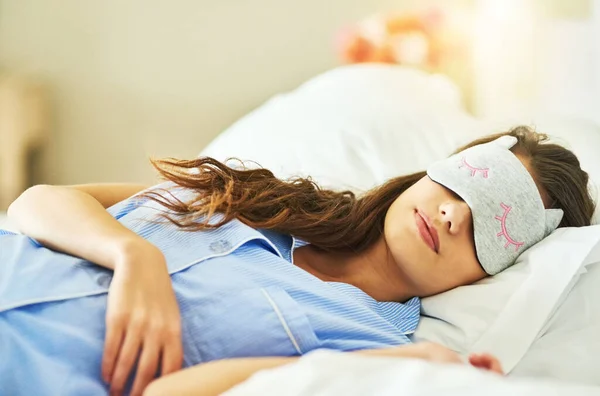 She needs her beauty rest. Cropped shot of an attractive young woman wearing a sleep mask while lying in bed. — Stock Photo, Image