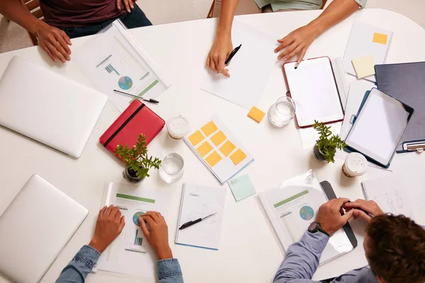 Todo en un día de trabajo. Foto de alto ángulo de un grupo de empresarios que trabajan juntos alrededor de una mesa en una oficina. — Foto de Stock