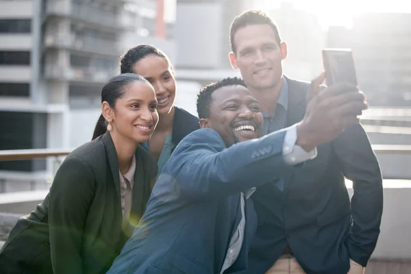 Takım ruhunu harekete geçiriyor. Bir grup iş adamının, şehrin arka planında selfie çekerken çekilmiş fotoğrafı.. — Stok fotoğraf