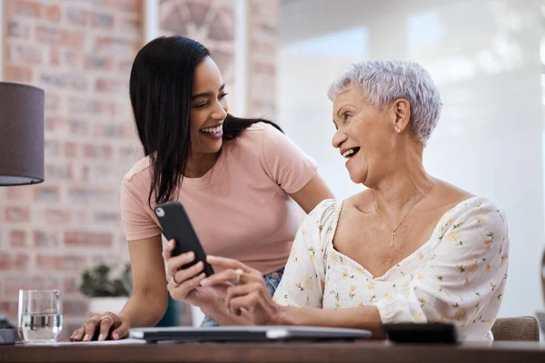 La forma inteligente de invertir esos ahorros. Fotografía de una mujer joven usando un teléfono inteligente con su anciana madre mientras pasaba por las finanzas en casa. — Foto de Stock