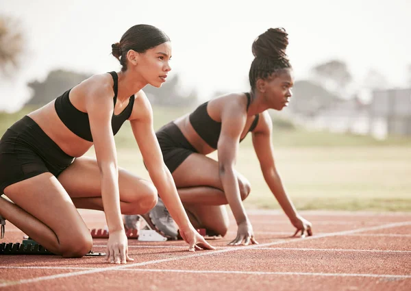 Es uno contra uno. Recortado disparo de dos jóvenes atletas atractivos comenzando su carrera en una pista. — Foto de Stock