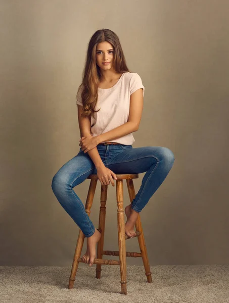 Tudod, milyen tökéletes vagy? Stúdió lövés egy gyönyörű fiatal nő ül a széken, szemben a sima háttér. — Stock Fotó