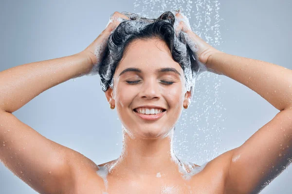 Um banho quente afasta o stress. Tiro de uma jovem mulher lavando o cabelo no chuveiro contra um fundo cinza. — Fotografia de Stock