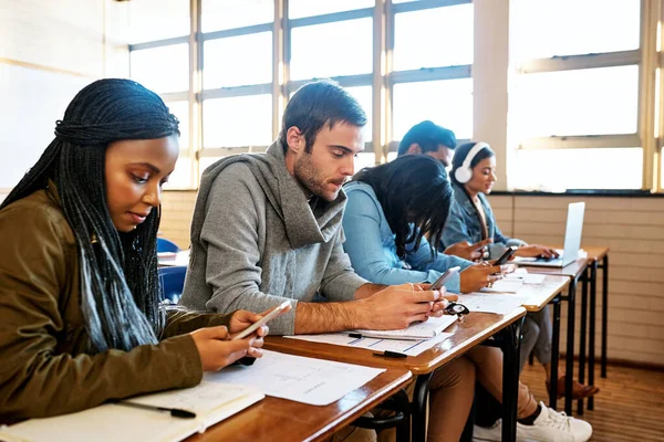 Мобильные телефоны это большое развлечение. Обрезанный снимок группы молодых студентов университета, работающих в классе. — стоковое фото