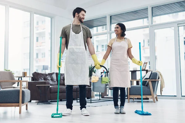 Con el trabajo en equipo, las tareas domésticas no tienen que ser difíciles. Foto de una feliz pareja joven fregando el suelo juntos en casa. —  Fotos de Stock