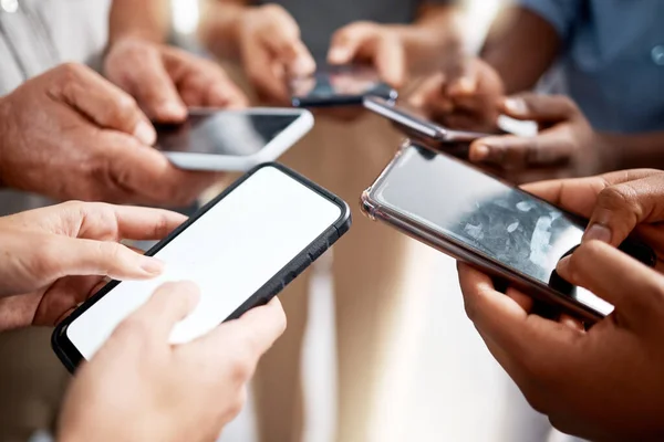 Verbinden Sie sich mit Gleichgesinnten. Aufnahme einer Gruppe unkenntlich gemachter Geschäftsleute mit ihren Smartphones in einem modernen Büro. — Stockfoto