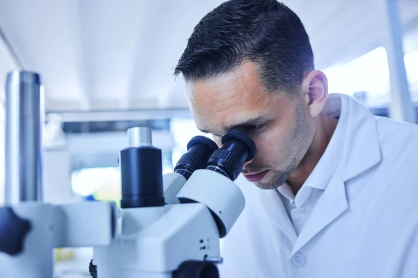 Ser saker som det mänskliga ögat inte kan se. Beskuren bild av en stilig ung manlig forskare som arbetar med ett mikroskop i sitt labb. — Stockfoto