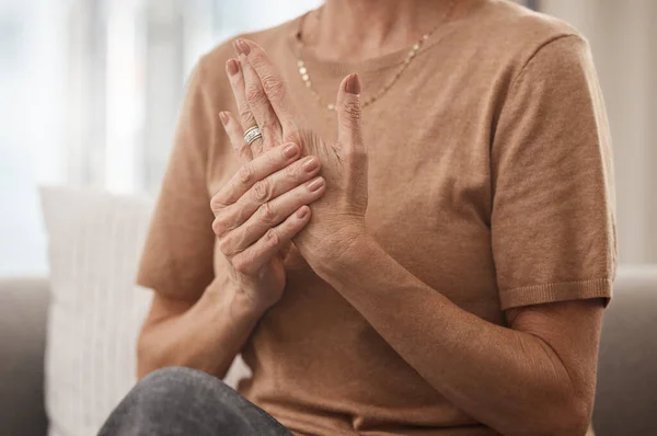 Help, my joints hurt. Shot of an unrecognisable woman experiencing pain in her hand at home. — Stock Photo, Image