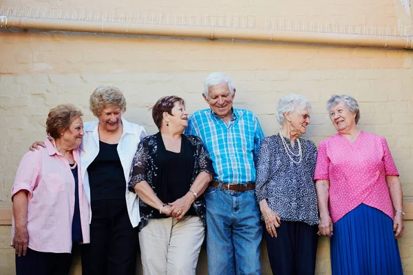 Quanto mais velhos ficamos, mais gostamos da vida. Tiro de um grupo de idosos em pé contra uma parede fora. — Fotografia de Stock