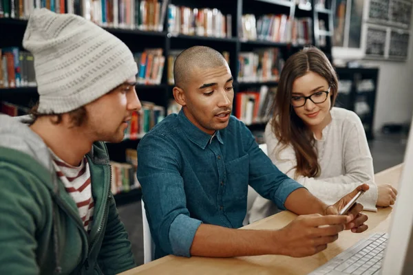 Vou partilhar esta ligação com vocês... foto de alto ângulo de três jovens universitários a estudar na biblioteca. — Fotografia de Stock