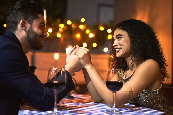 Ficaremos juntos para sempre. Tiro de um jovem casal alegre de mãos dadas enquanto olham uns para os outros olhos sobre uma vela iluminada jantar data à noite. — Fotografia de Stock