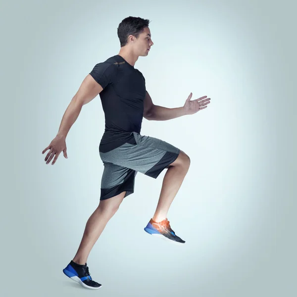 Mantén tus límites corporales en mente. Estudio de un joven atlético corriendo sobre un fondo gris. —  Fotos de Stock