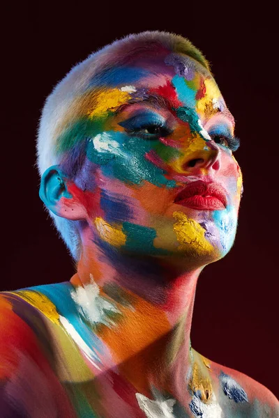 Ο κόσμος είναι ο καμβάς μου και δημιουργώ την πραγματικότητά μου. Στιγμιότυπο μιας νεαρής γυναίκας που ποζάρει με πολύχρωμο χρώμα στο πρόσωπό της. — Φωτογραφία Αρχείου