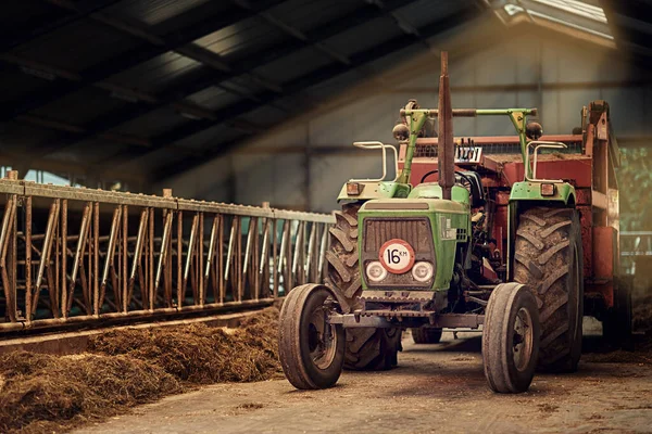 Viejos fieles. Un disparo de un viejo tractor oxidado parado en un granero vacío. — Foto de Stock