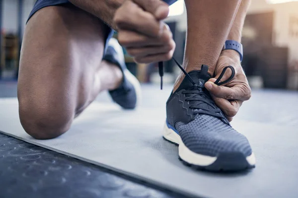 Schnürsenkel für ein gutes Training. Nahaufnahme eines nicht wiederzuerkennenden Mannes, der seine Schnürsenkel in einem Fitnessstudio bindet. — Stockfoto