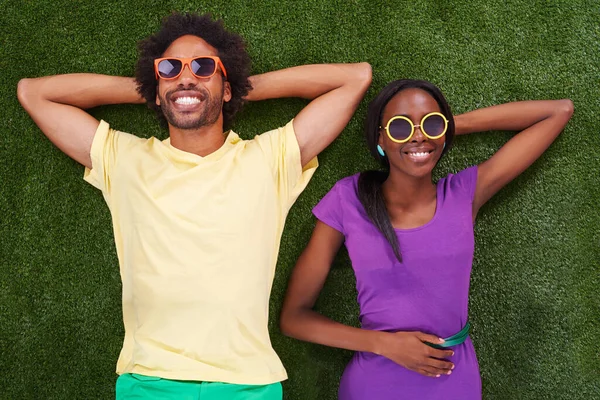 Vi tog det lugnt. Ett ungt afrikanskt par som ligger på gräset tillsammans. — Stockfoto