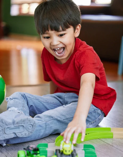 Los niños pequeños simplemente aman los trenes, aviones, camiones y coches. Tiro de un adorable niño jugando con juguetes en casa. — Foto de Stock