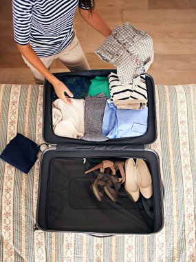 Time to hit the road. High angle shot of a woman packing a suitcase on a bed. clipart