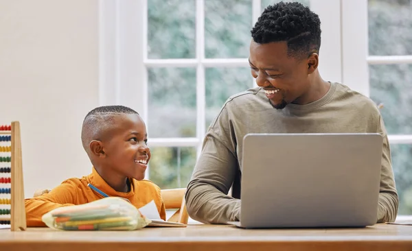 Kun je me helpen? Shot van een jonge vader met behulp van een laptop, terwijl zijn zoon doet huiswerk thuis. — Stockfoto