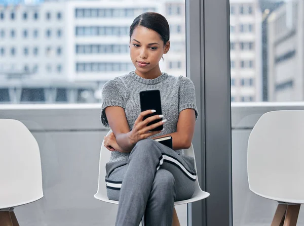Navegar pelas redes sociais para acalmar os nervos. Tiro de uma jovem empresária usando um telefone em uma sala de espera. — Fotografia de Stock