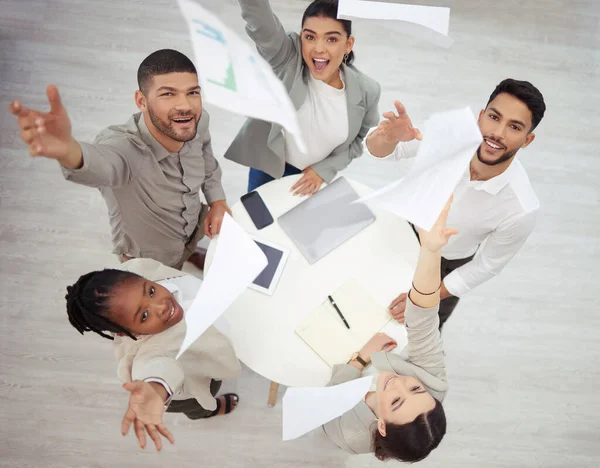 O valor da realização reside na realização. Fotografia aérea de um grupo diversificado de empresários jogando papelada no ar em celebração enquanto no escritório. — Fotografia de Stock