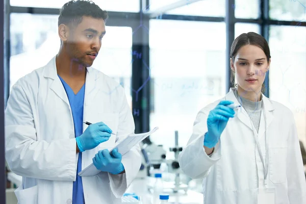 Faire les maths pour prouver leur théorie. Prise de vue de deux scientifiques résolvant des équations sur un écran de verre dans un laboratoire. — Photo