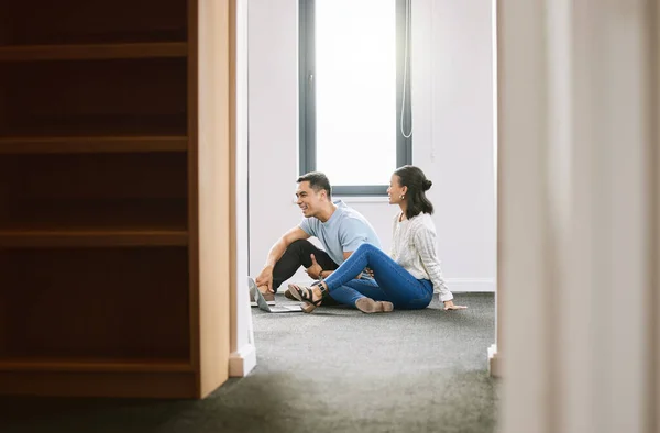 Temos tanto para fazer nesta casa. Tiro de comprimento total de um jovem casal sentado no chão juntos na nova casa e usando um laptop. — Fotografia de Stock