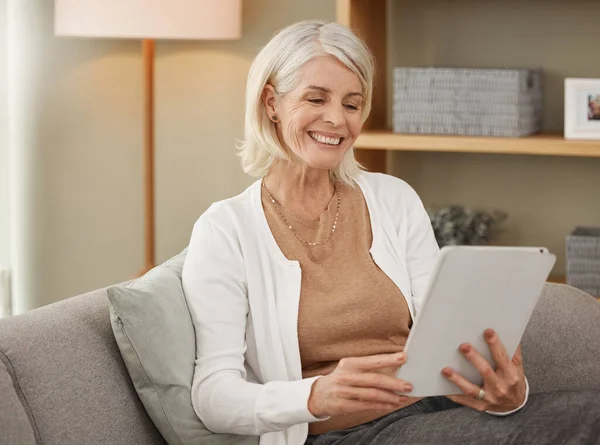 Ontspanning begint nu. Foto van een volwassen vrouw met behulp van een digitale tablet op de bank thuis. — Stockfoto