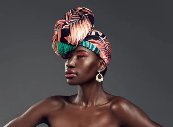 Si ', puoi essere femminile e comunque feroce. Studio girato di una bella giovane donna che indossa un tradizionale copricapo africano su uno sfondo grigio. — Foto Stock