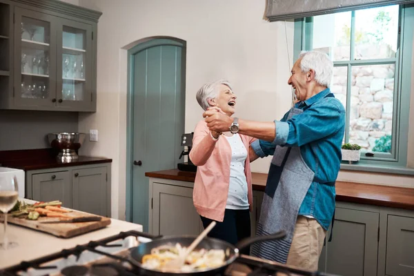 맛있는 음식먹고 웃어. 집 부엌에서 요리를 하고 있는 나이든 부부가 춤을 추고 있는 모습 이 총에 맞은 사진. — 스톡 사진
