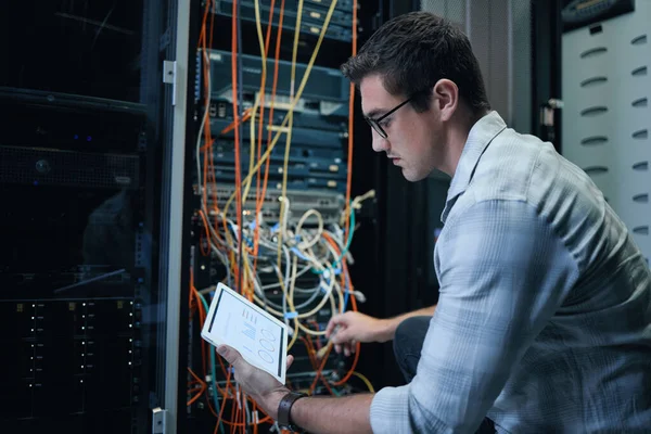 Haciendo diagnósticos. Fotografía recortada de un guapo joven programador masculino trabajando en una tableta en una sala de servidores. — Foto de Stock