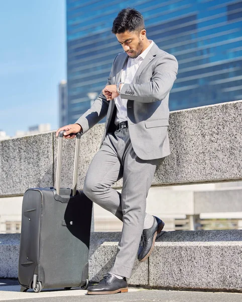 Espero que no vaya a llegar tarde. Fotografía de un joven empresario comprobando el tiempo mientras estaba de pie con una maleta en la ciudad. — Foto de Stock